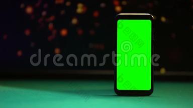智能手机，桌上有绿色屏幕，背景灯闪闪发光
